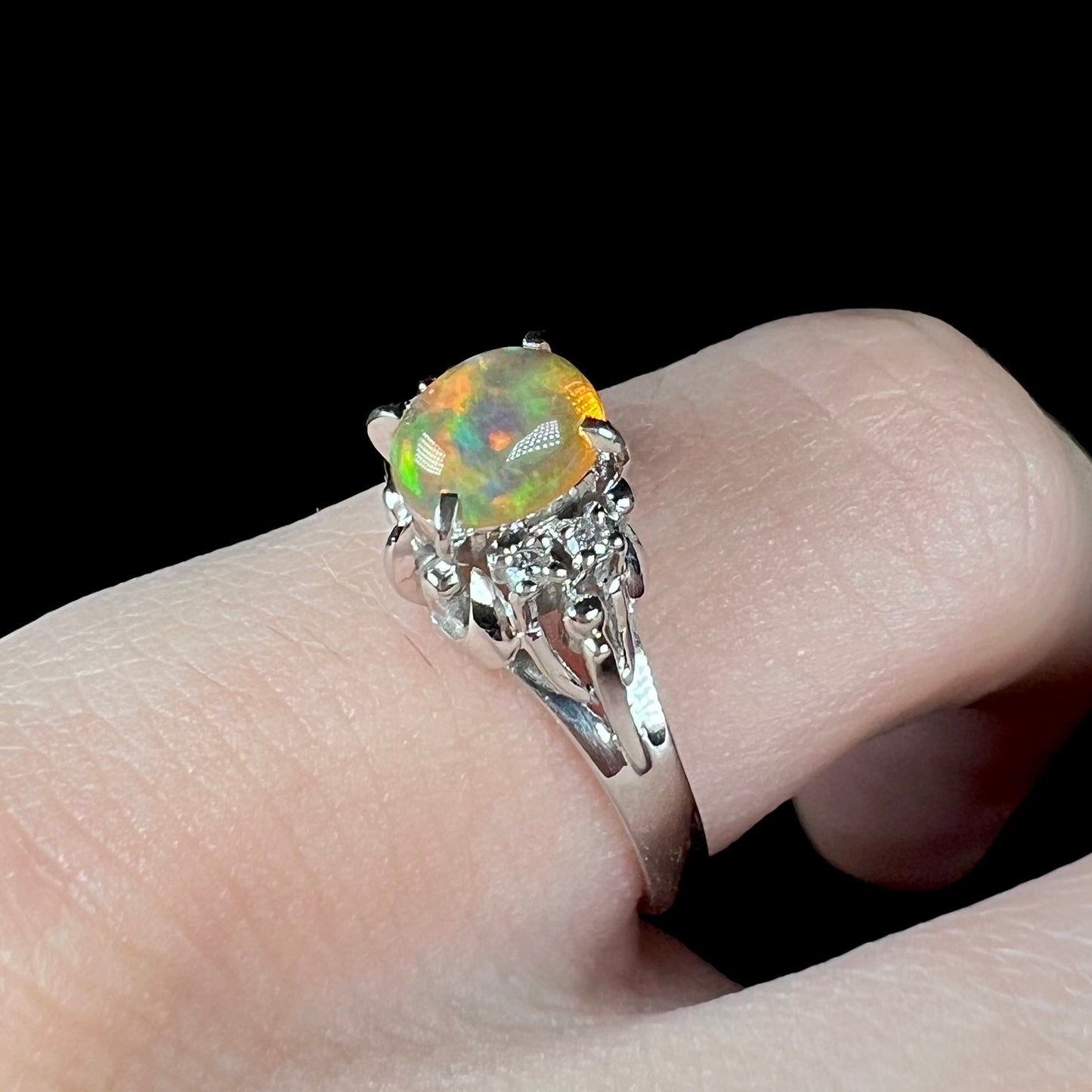 A platinum, diamond accented ring prong-set with an oval cabochon cut Mexican fire opal.