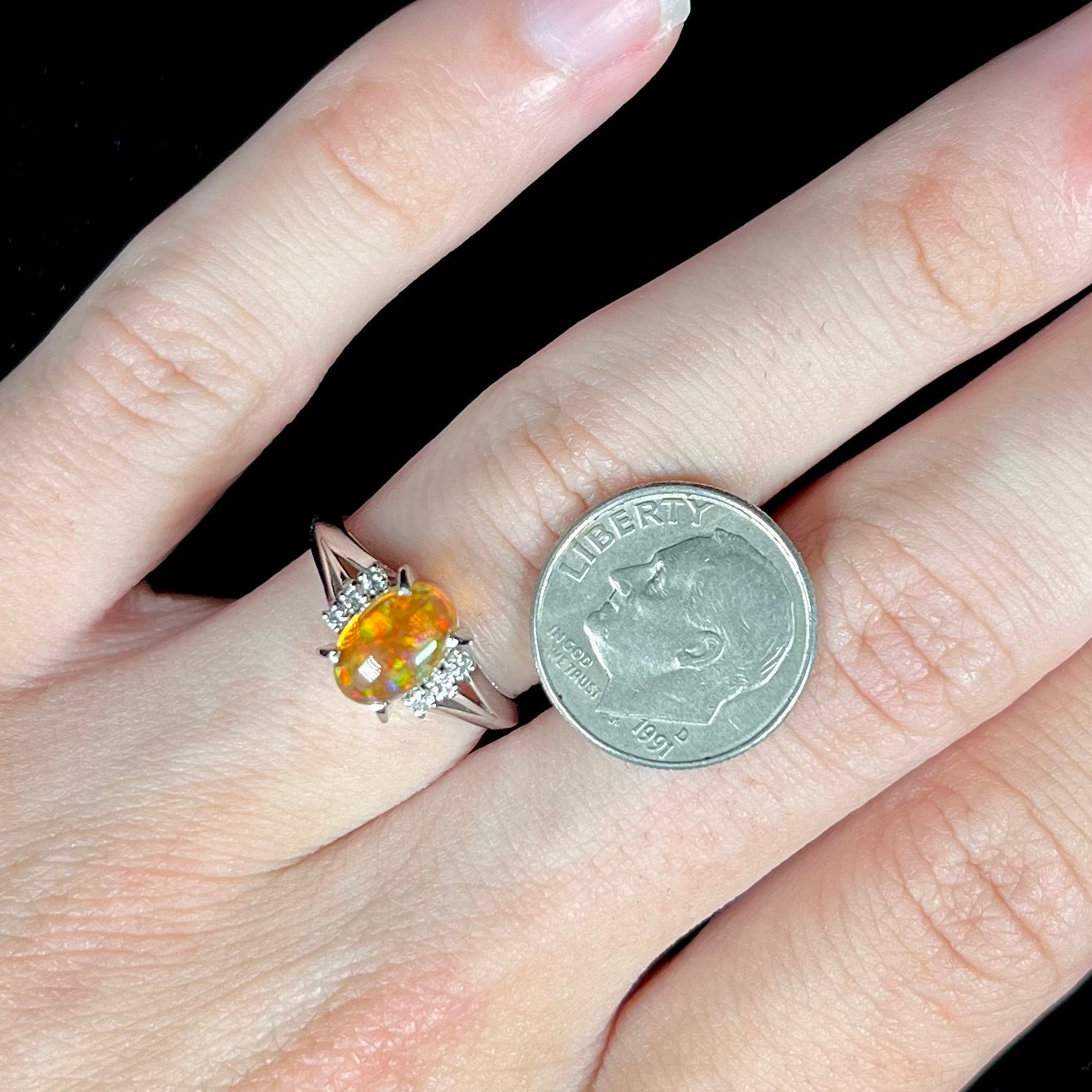 A platinum filigree and diamond-accented Mexican fire opal ring.  The opal is orange with green fire.