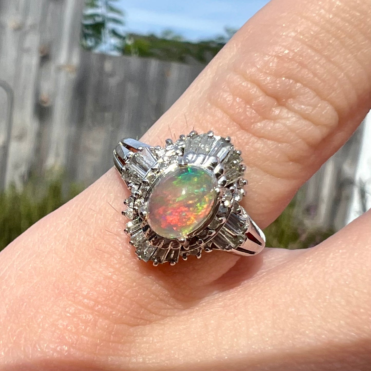 A platinum ring mounted with a Mexican fire opal and baguette cut diamond accents.