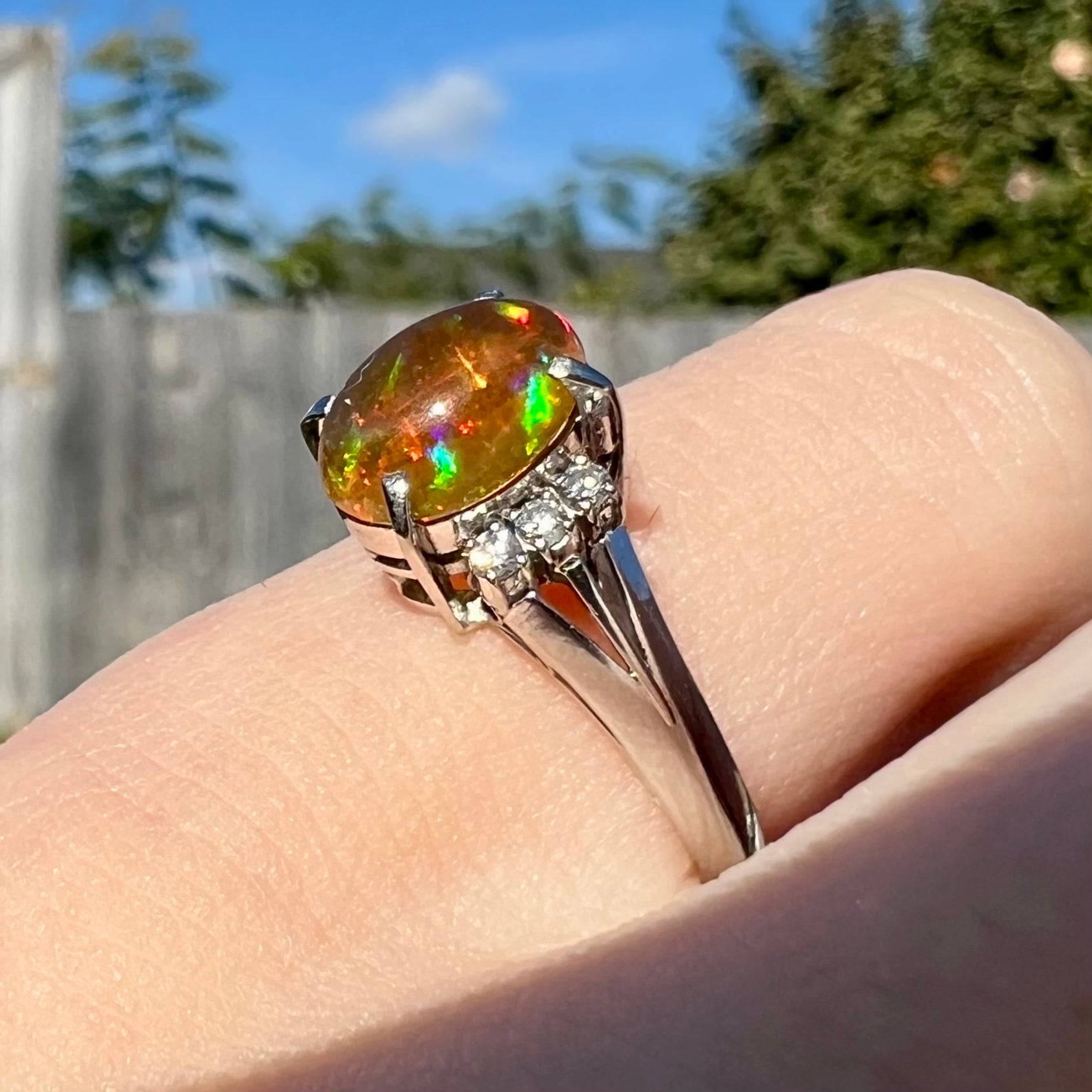 A platinum filigree and diamond-accented Mexican fire opal ring.  The opal is orange with green fire.