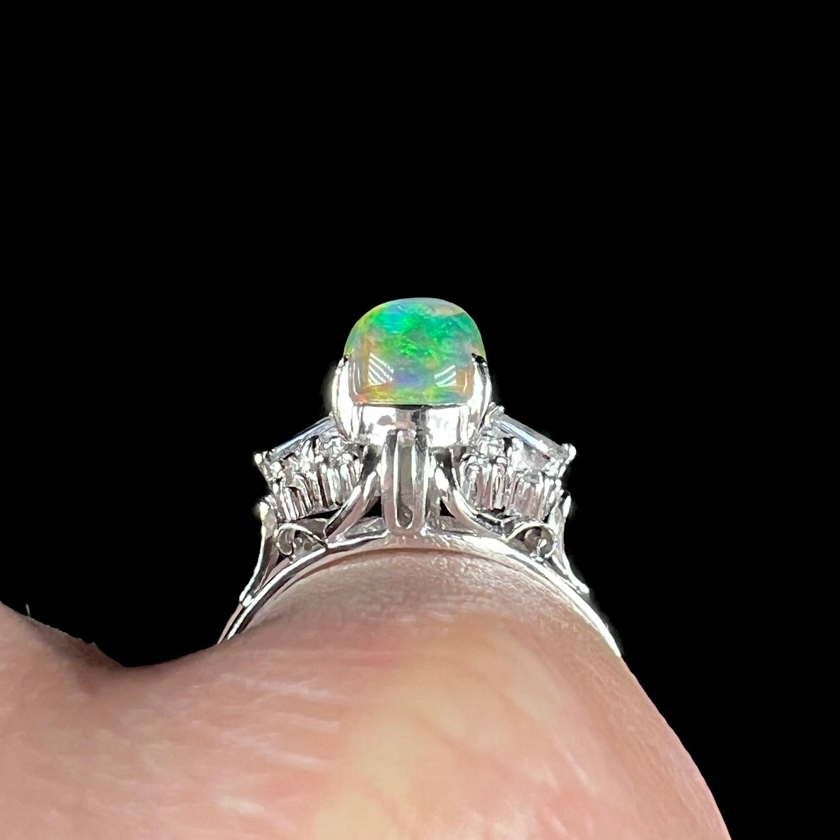 A platinum filigree ring mounted with a high-domed Mexican fire opal and baguette cut diamond accents.