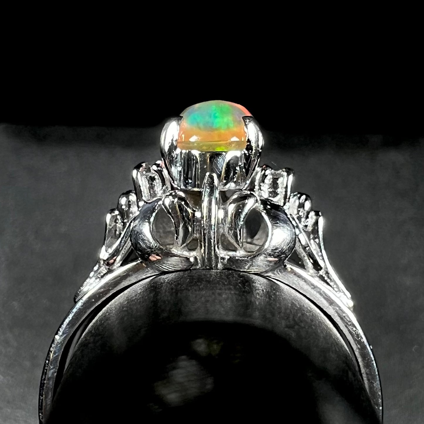 A platinum, diamond accented ring prong-set with an oval cabochon cut Mexican fire opal.