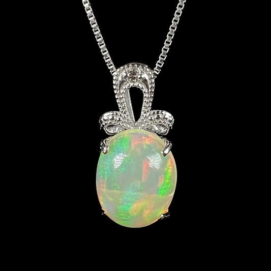 An oval cut Ethiopian opal mounted in a diamond-accented, 18 karat white gold pendant on a box chain.