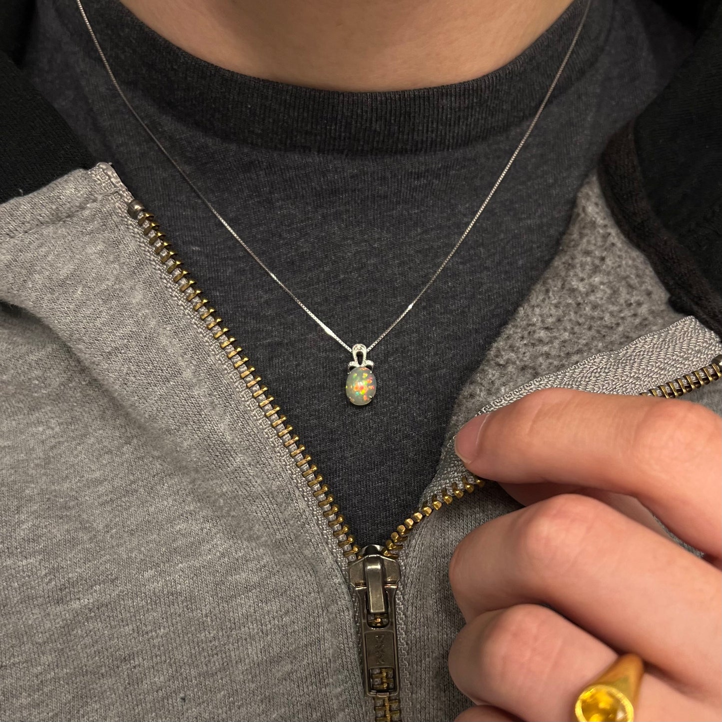 An oval cut Ethiopian opal mounted in a diamond-accented, 18 karat white gold pendant on a box chain.