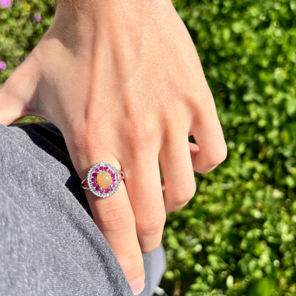 A sterling silver Ethiopian opal ring mounted with a halo of white CZs and another halo of synthetic pink sapphires.