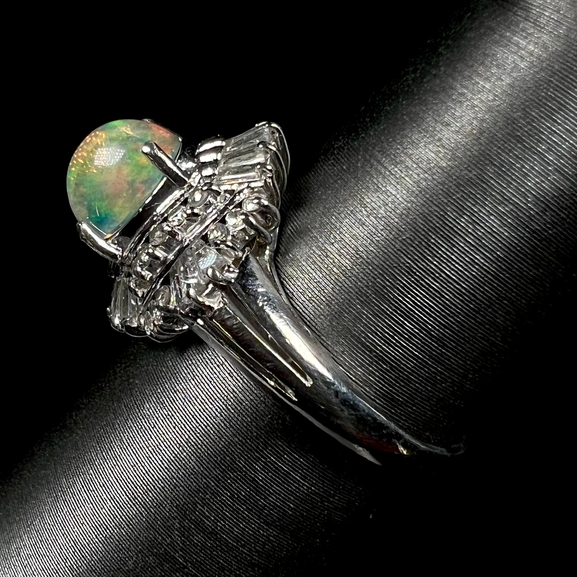 A platinum ring mounted with a Mexican fire opal and baguette cut diamond accents.