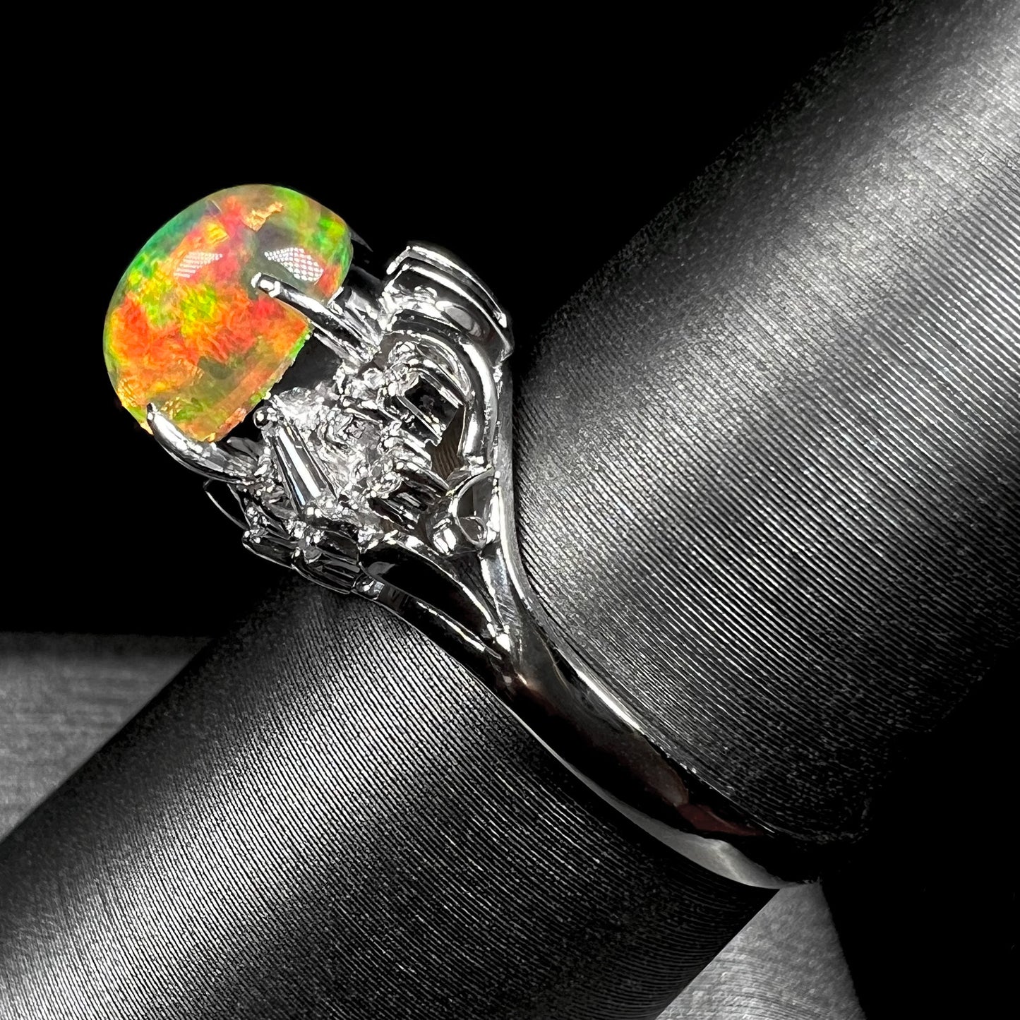 A platinum filigree ring mounted with a high-domed Mexican fire opal and baguette cut diamond accents.