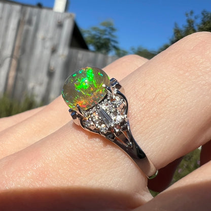 A platinum filigree ring mounted with a high-domed Mexican fire opal and baguette cut diamond accents.