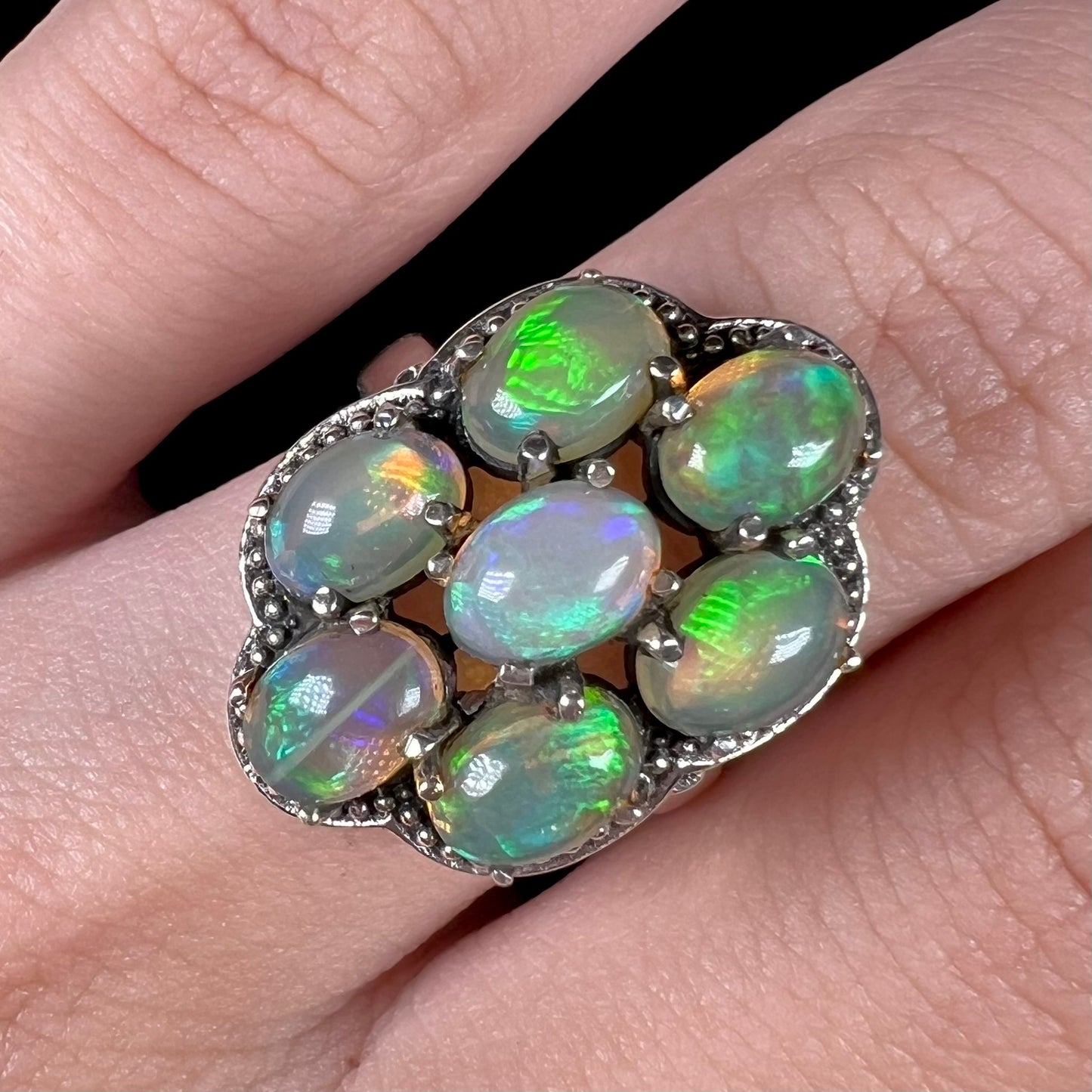 A sterling silver cluster ring prong-set with seven green Ethiopian fire opals.