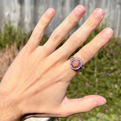 A sterling silver Ethiopian opal ring mounted with a halo of white CZs and another halo of synthetic pink sapphires.