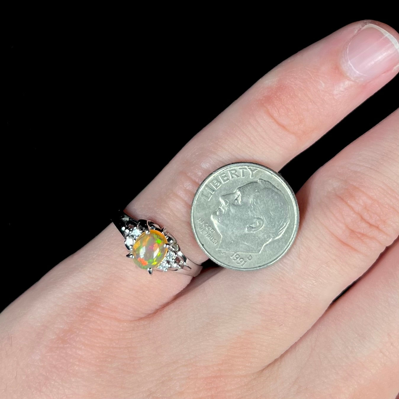 A platinum, diamond accented ring prong-set with an oval cabochon cut Mexican fire opal.