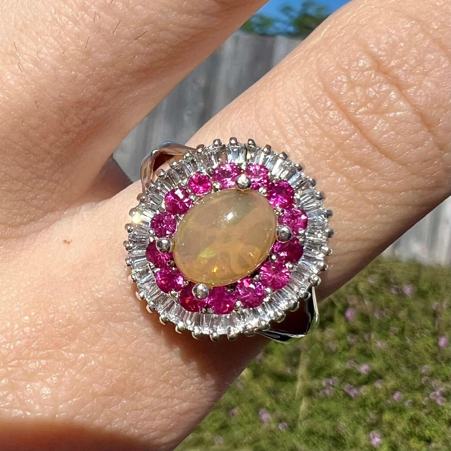 A sterling silver Ethiopian opal ring mounted with a halo of white CZs and another halo of synthetic pink sapphires.