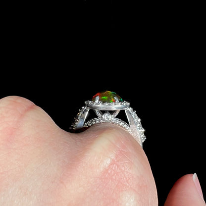 A CZ-accented sterling silver halo ring mounted with a smoked Ethiopian fire opal.  The opal plays green, red, and blue colors.