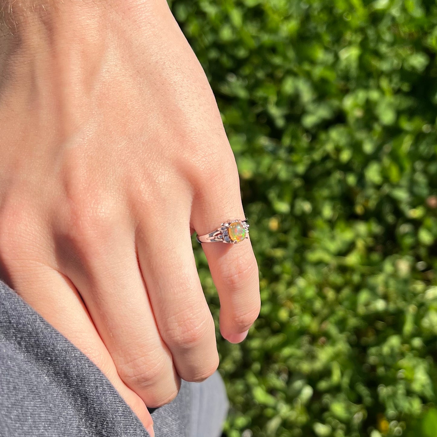 A platinum, diamond accented ring prong-set with an oval cabochon cut Mexican fire opal.