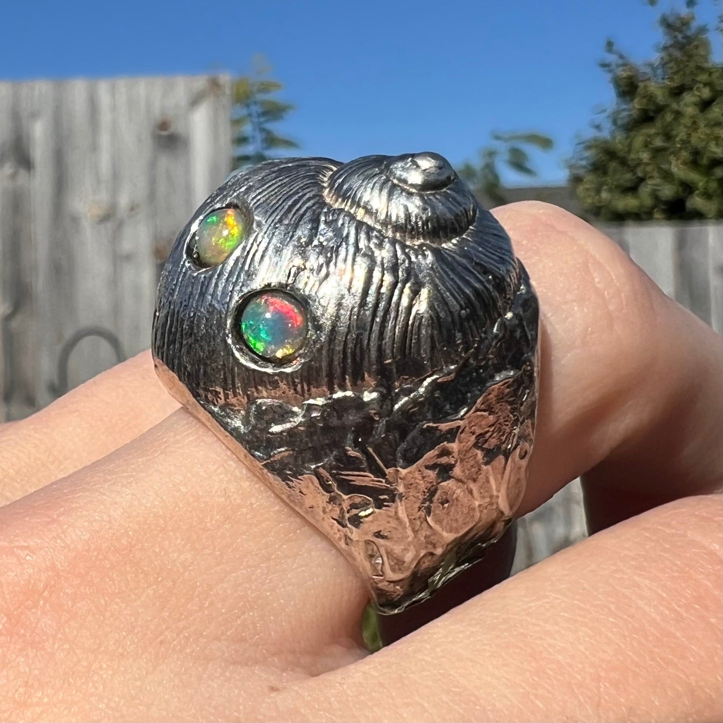 A large, three dimensional sterling silver snail seashell ring set with three round Ethiopian fire opal stones.