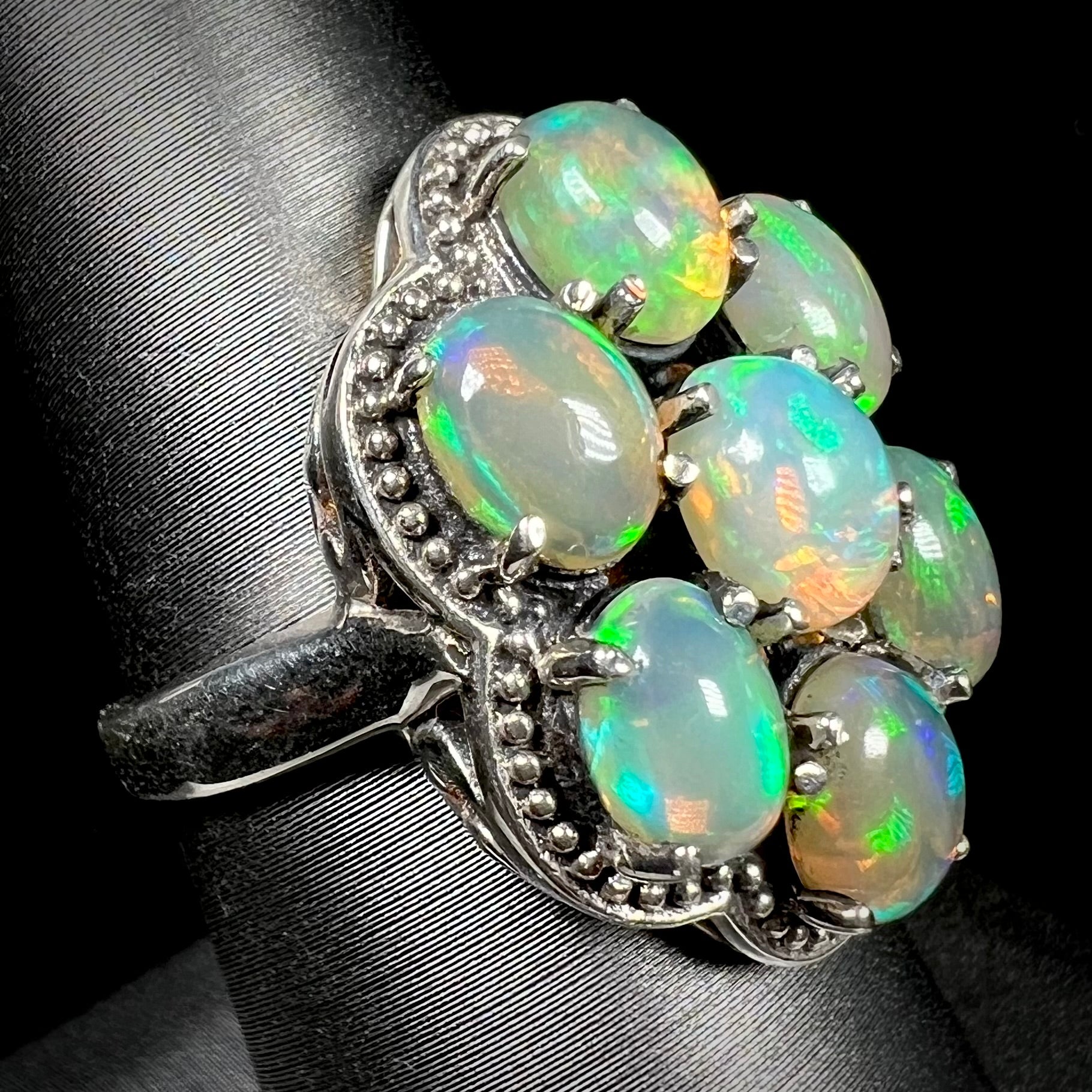 A sterling silver cluster ring prong-set with seven green Ethiopian fire opals.