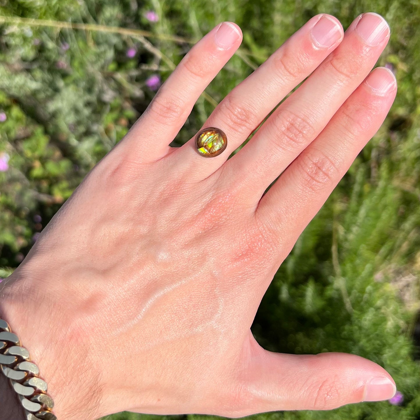 A loose, green, blue, and orange banded fire agate cabochon.