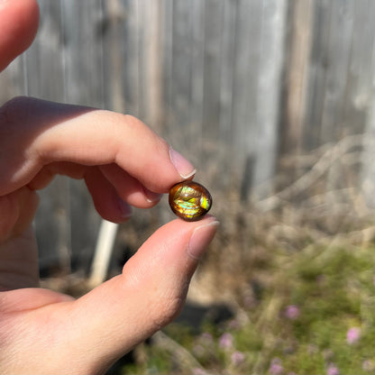 A loose, green, blue, and orange banded fire agate cabochon.