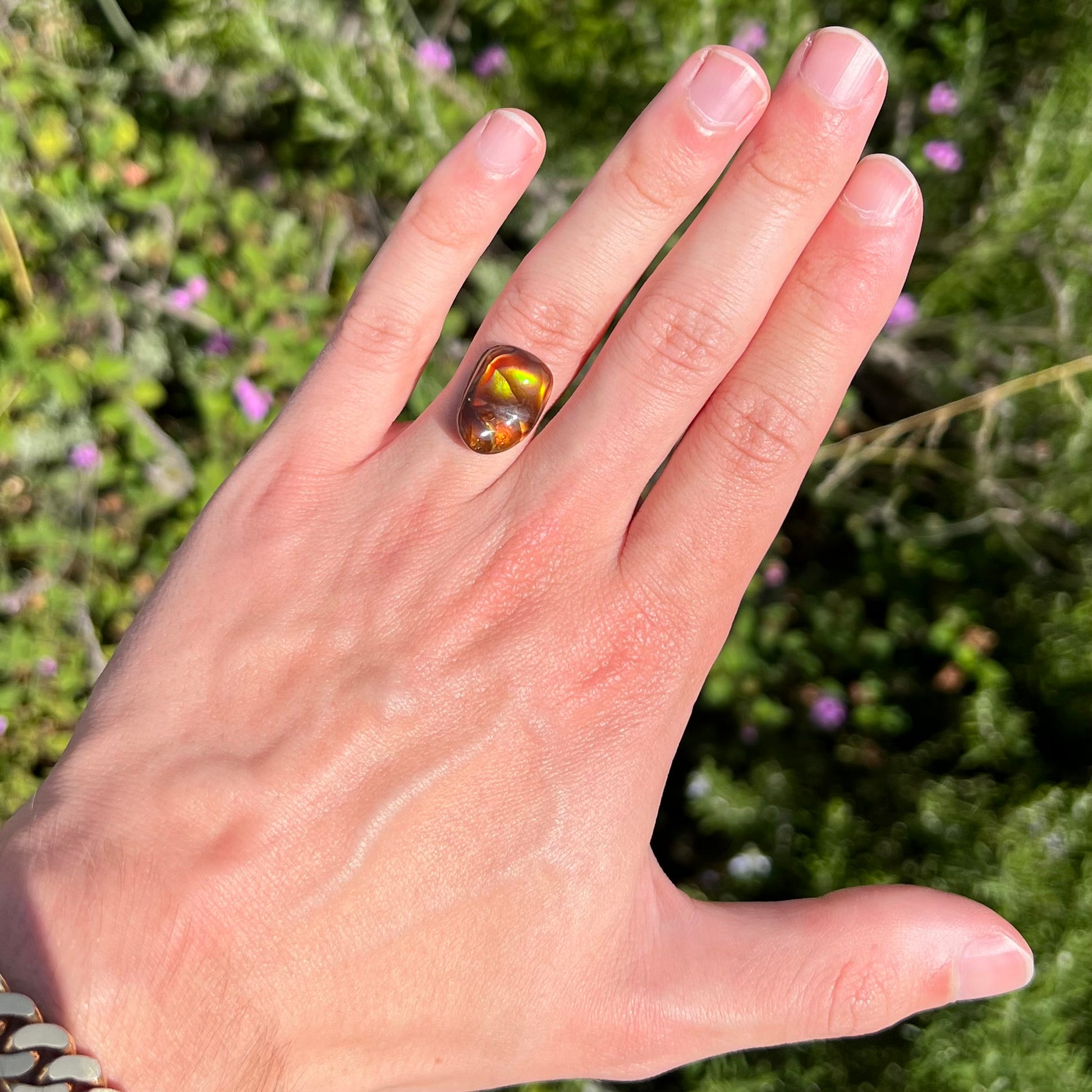 A loose fire agate cabochon.  The stne shows green and orange iridescence on a brown body tone.