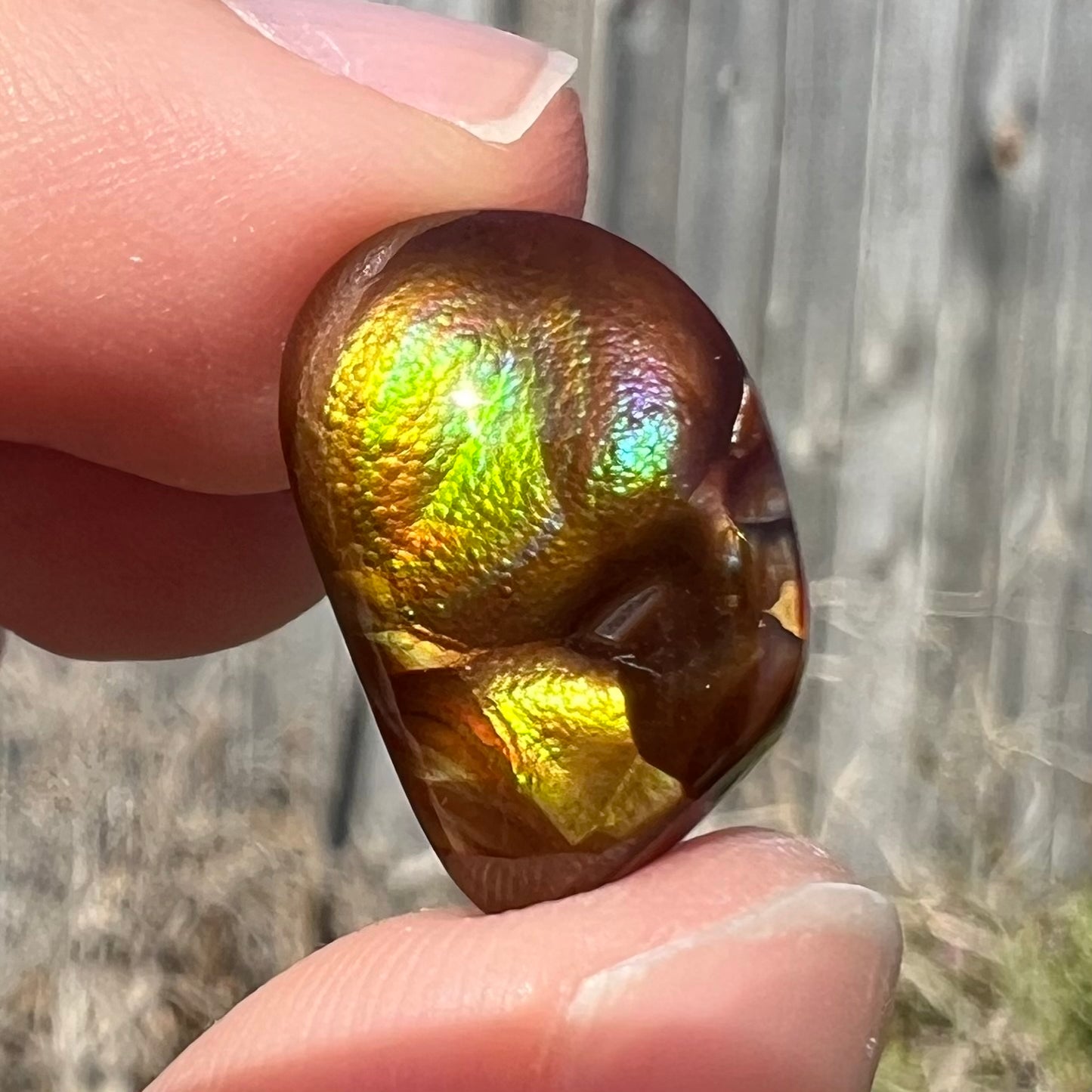 A brightly reflective Mexican fire agate cabochon.  The stone has a strong green iridescence.