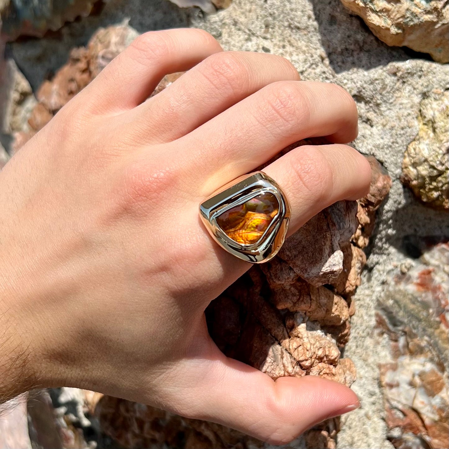 A heavy, yellow gold men's ring mounted with a Mexican fire agate stone.  The fire agate has orange, green, red, and purple colors.