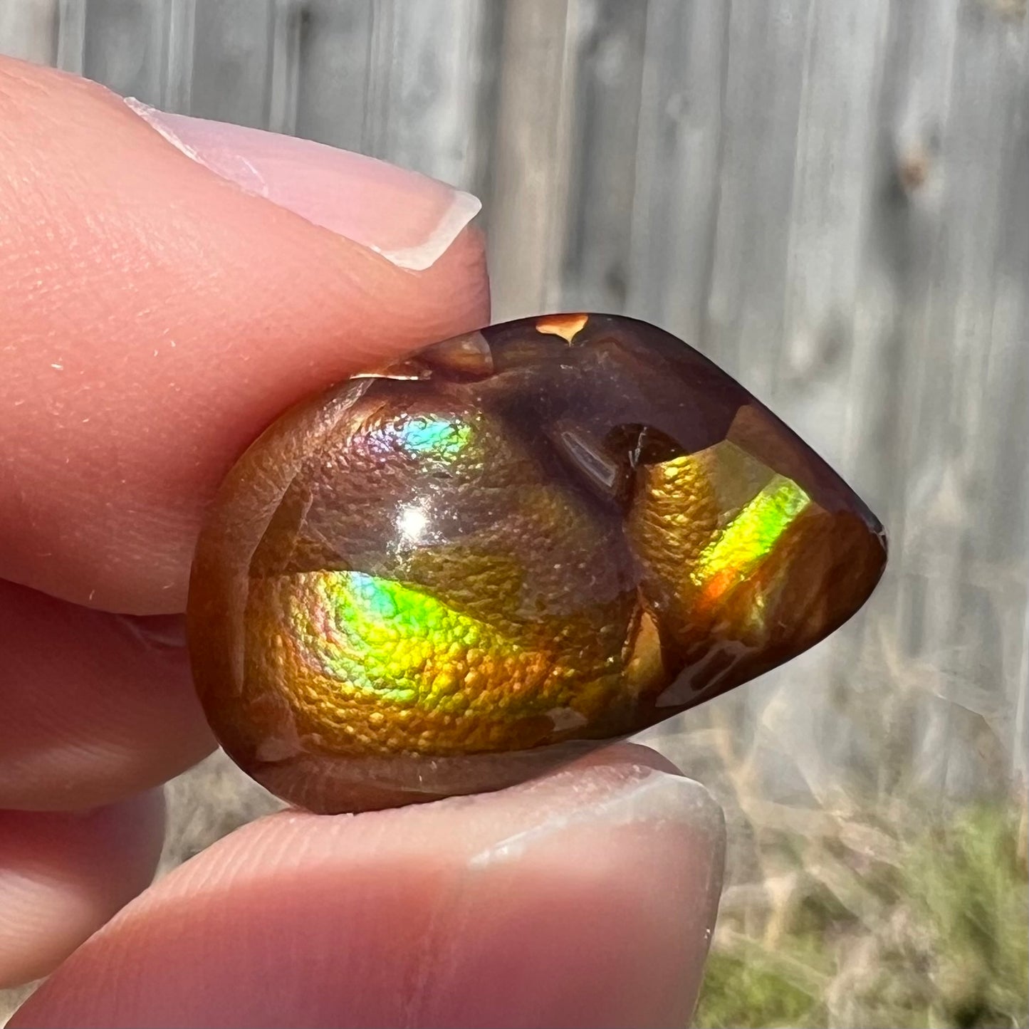 A brightly reflective Mexican fire agate cabochon.  The stone has a strong green iridescence.