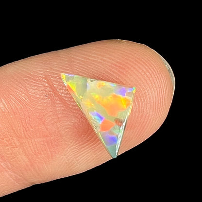 A triangle shaped Australian fire opal stone with red and orange colors.