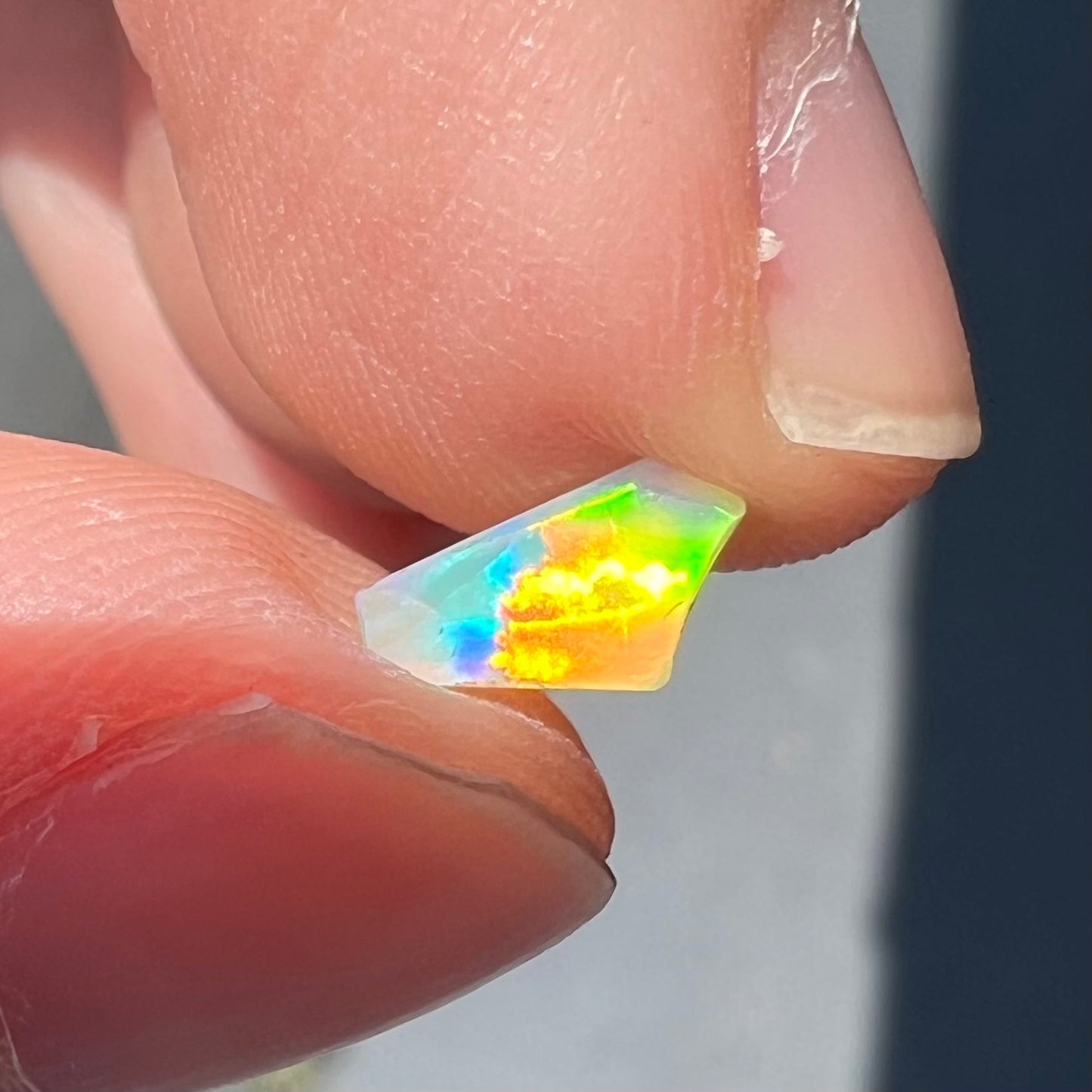 A loose, Australian fire opal chip.  The stone shines red, green, and yellow colors.