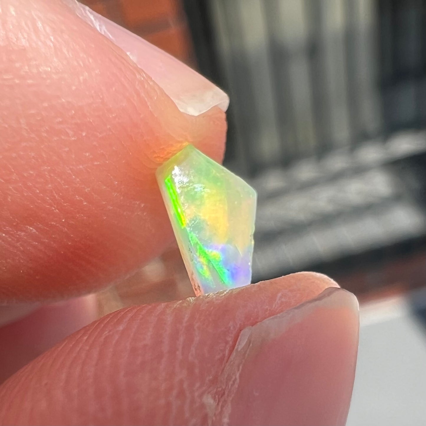 A loose, Australian fire opal chip.  The stone shines red, green, and yellow colors.