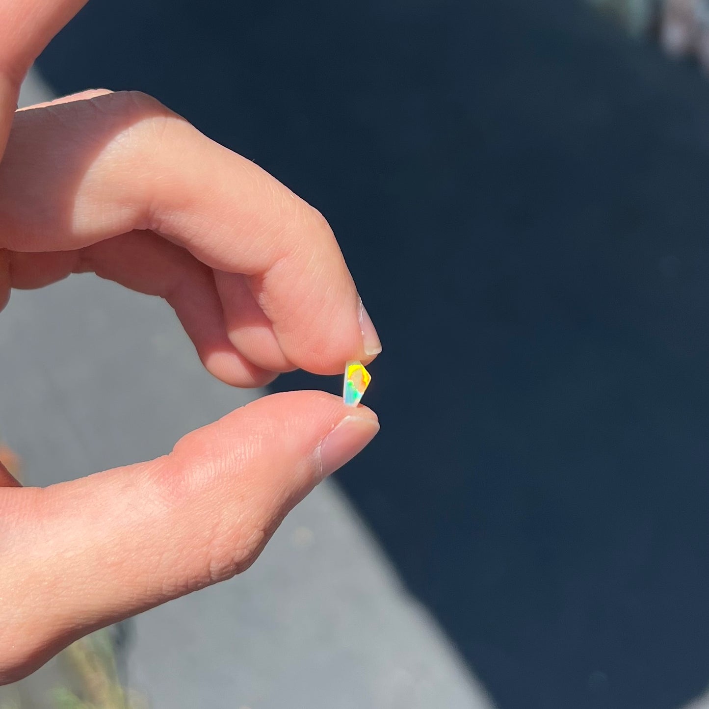 A loose, Australian fire opal chip.  The stone shines red, green, and yellow colors.