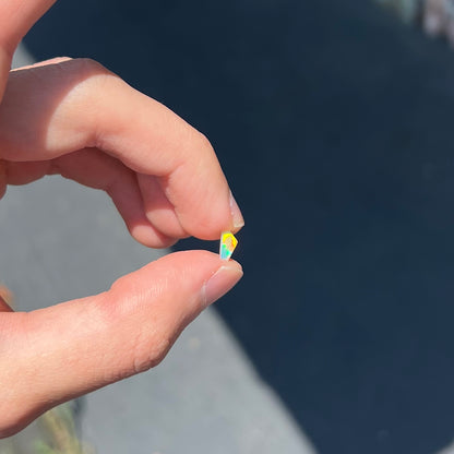 A loose, Australian fire opal chip.  The stone shines red, green, and yellow colors.