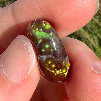 A loose, cabochon cut fire agate gemstone.  The stone resembles a foot with a green heel and yellow toes.