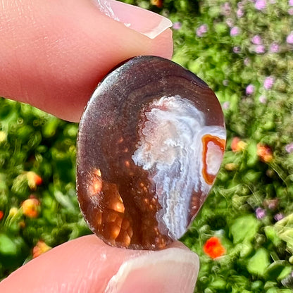 A loose, oval cabochon cut fire agate gemstone.  The stone is bubbly green with blue overtones.