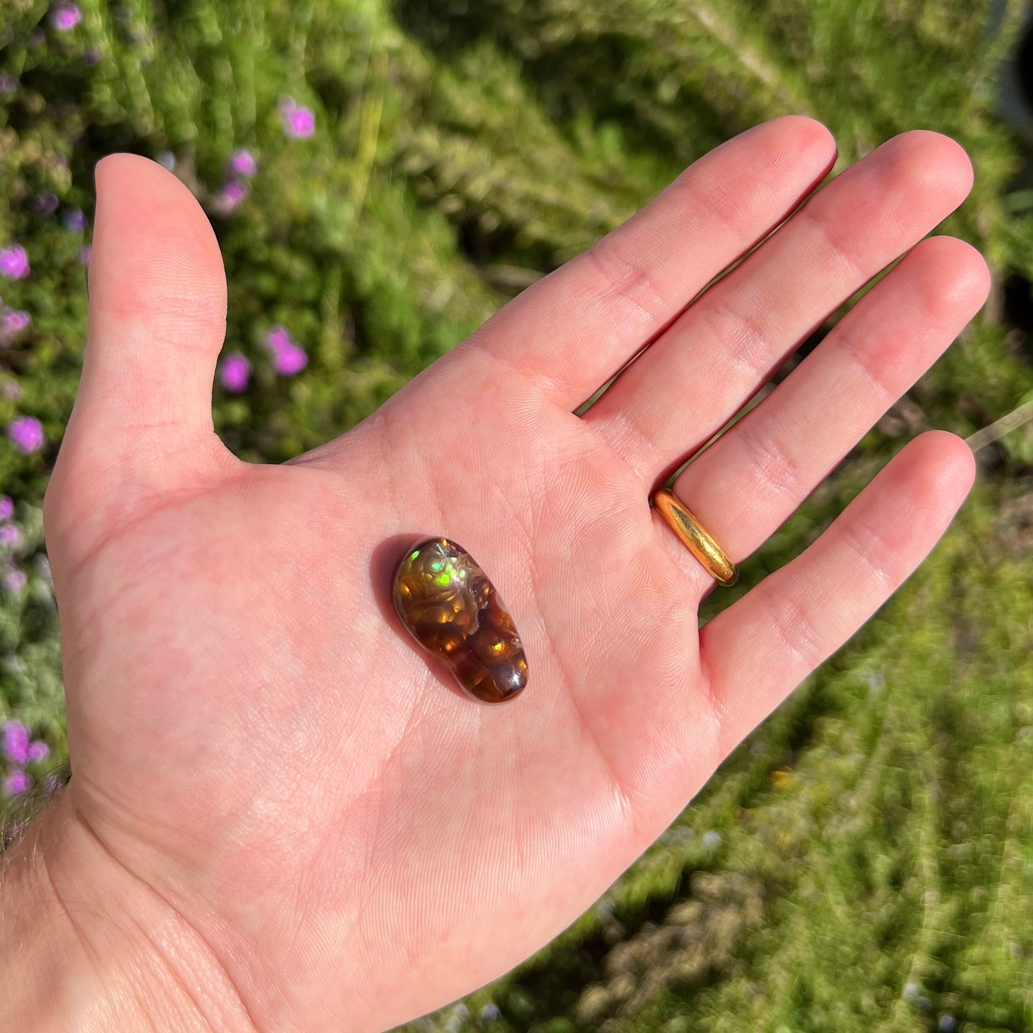 A loose fire agate cabochon.  The stone has iridescent green, yellow, and blue colors.