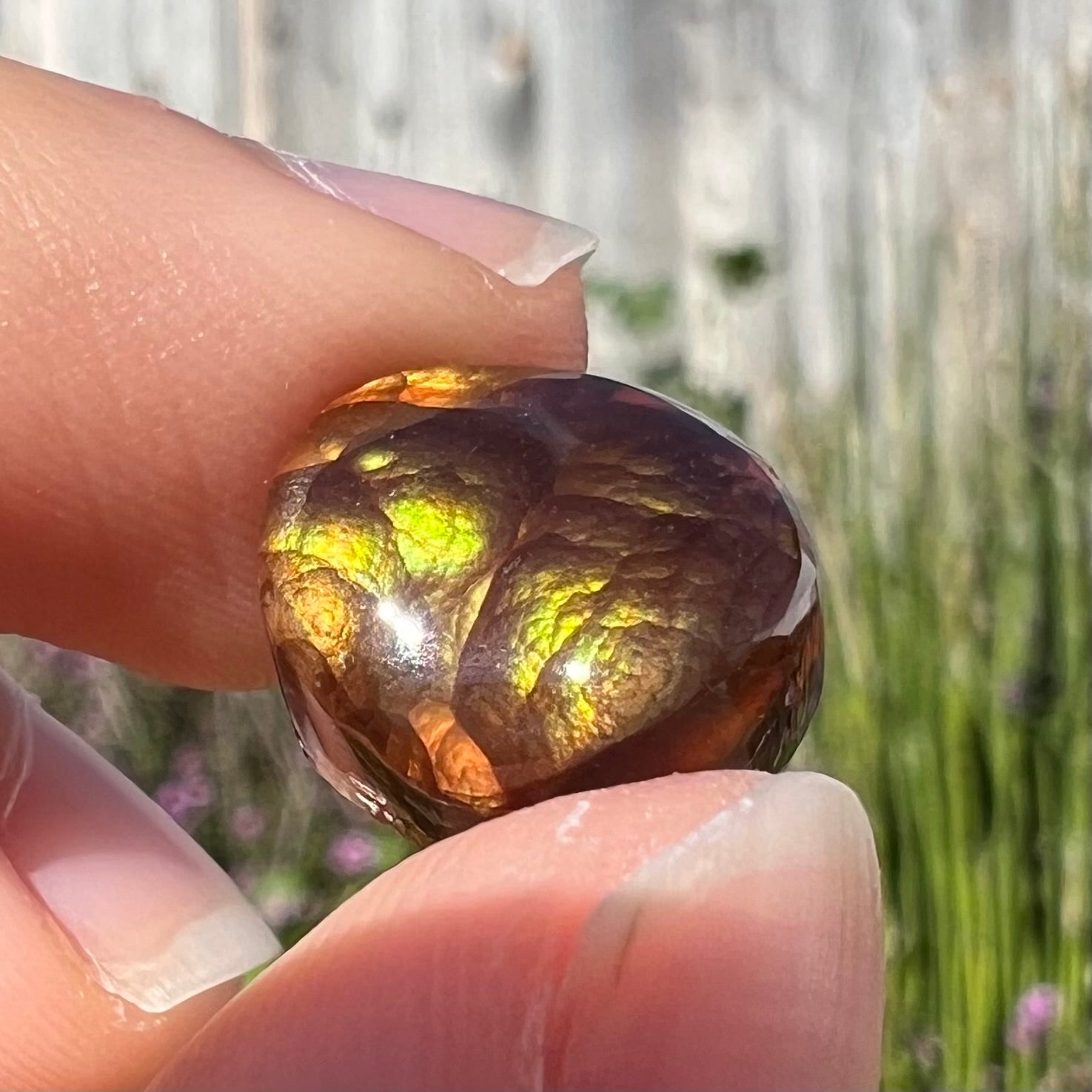 A loose, round Mexican fire agate stone.  The stone shines colors of green, yellow, and orange.