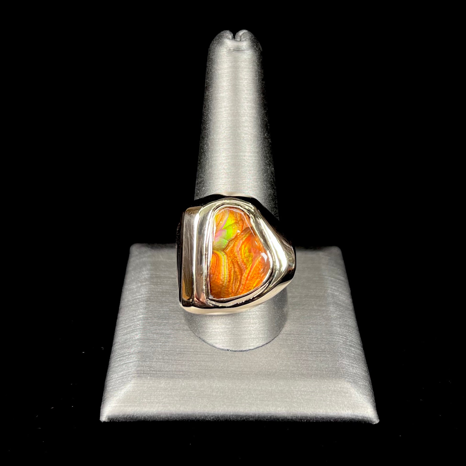 A heavy, yellow gold men's ring mounted with a Mexican fire agate stone.  The fire agate has orange, green, red, and purple colors.