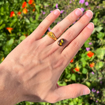 A loose, freefrom cabochon cut Mexican fire agate stone.  The stone has red, green, yellow, and purple banding.