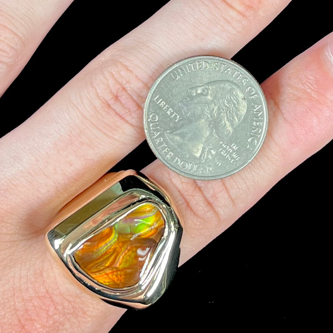 A heavy, yellow gold men's ring mounted with a Mexican fire agate stone.  The fire agate has orange, green, red, and purple colors.