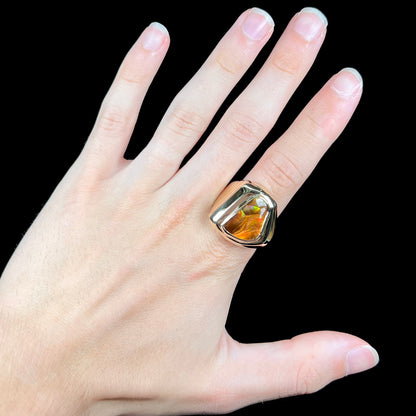 A heavy, yellow gold men's ring mounted with a Mexican fire agate stone.  The fire agate has orange, green, red, and purple colors.