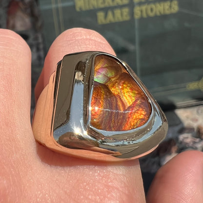 A heavy, yellow gold men's ring mounted with a Mexican fire agate stone.  The fire agate has orange, green, red, and purple colors.