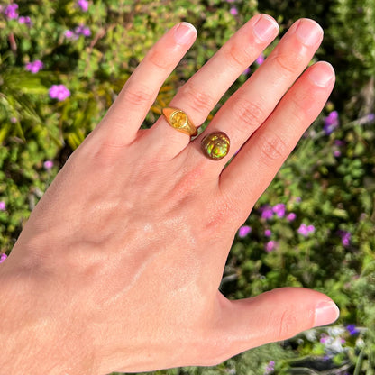 An iridescent green, yellow, and red Mexican fire agate stone.  The stone is an off-round cabochon.