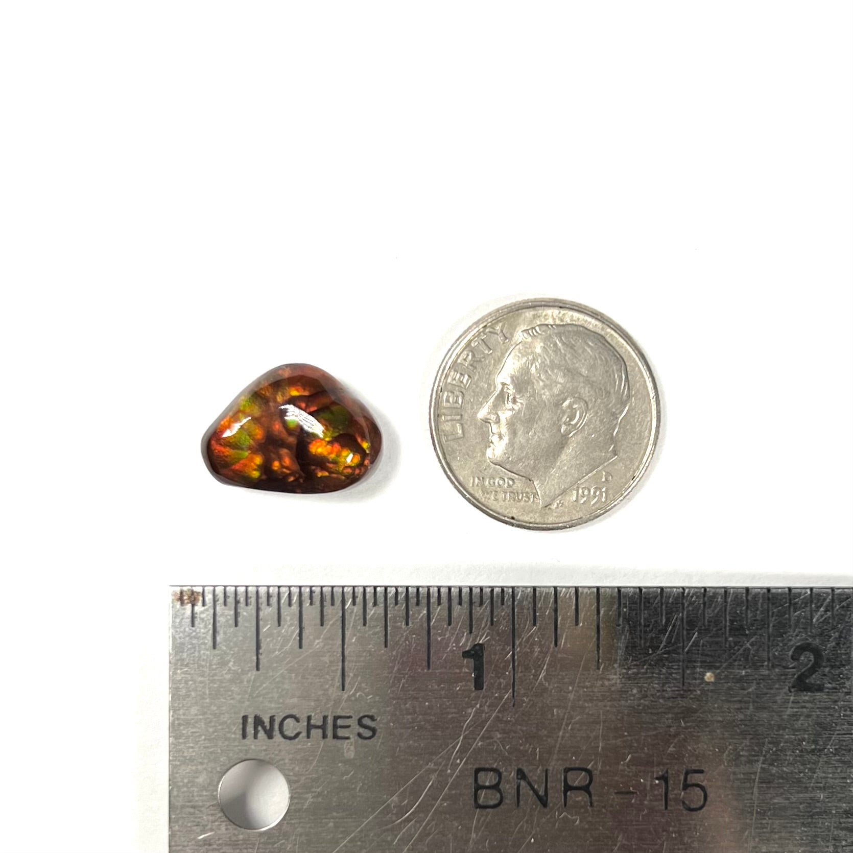 A loose, freeform fire agate gemstone.  The stone is red with green and orange banding.