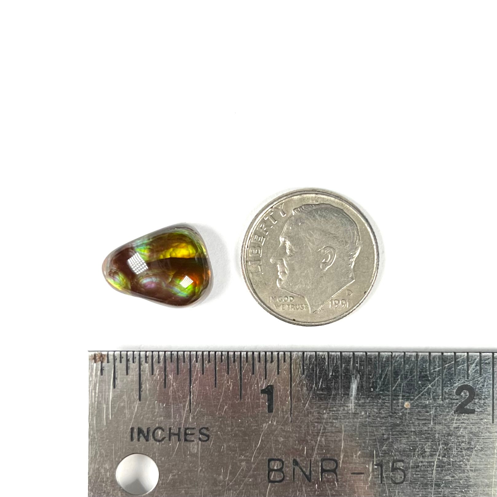 A freeform shaped fire agate cabochon with green and red iridescence.