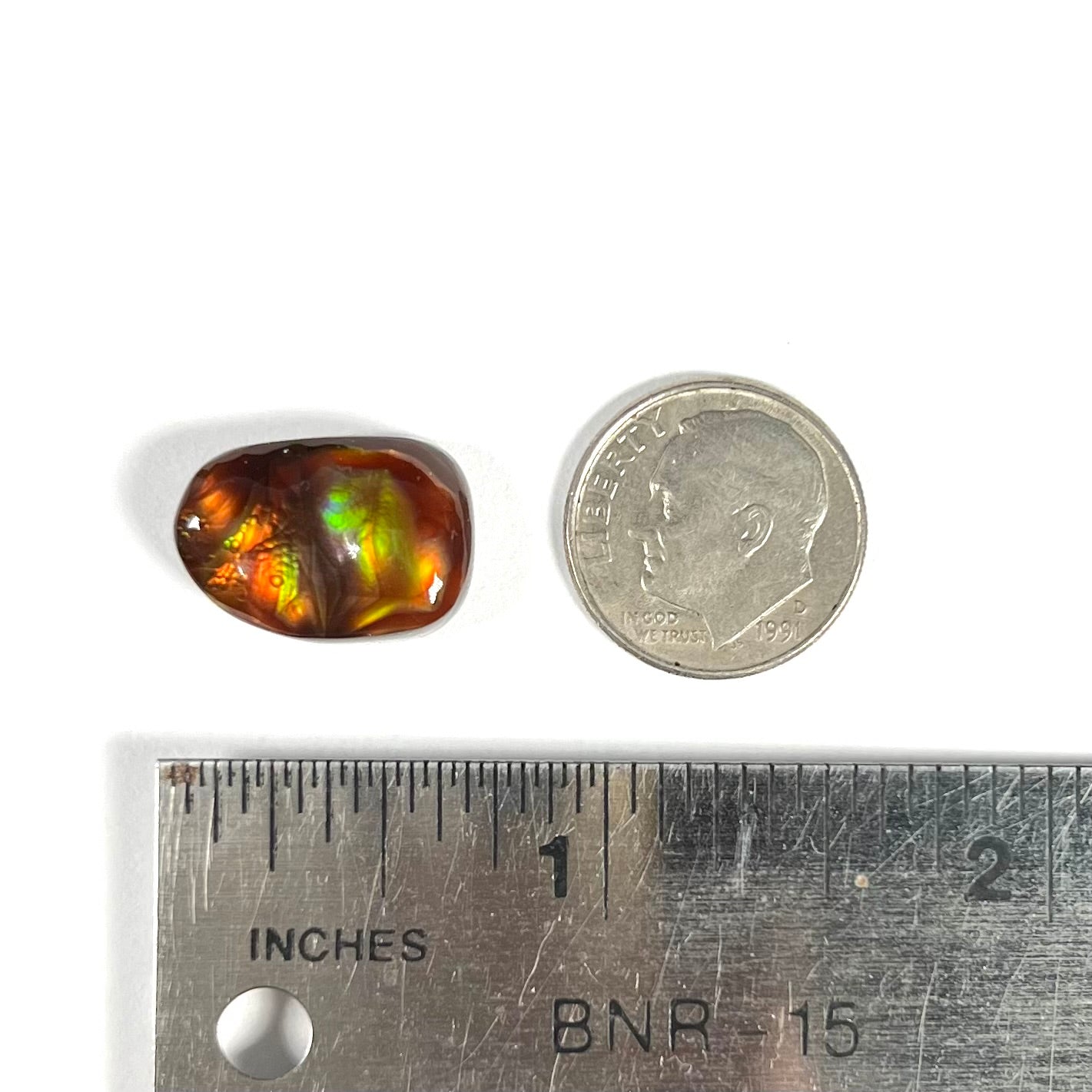 A loose fire agate cabochon.  The stne shows green and orange iridescence on a brown body tone.