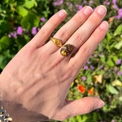 An oval cabochon cut Mexican fire agate stone.  The stone's predominant colors are green, yellow, orange, and blue.