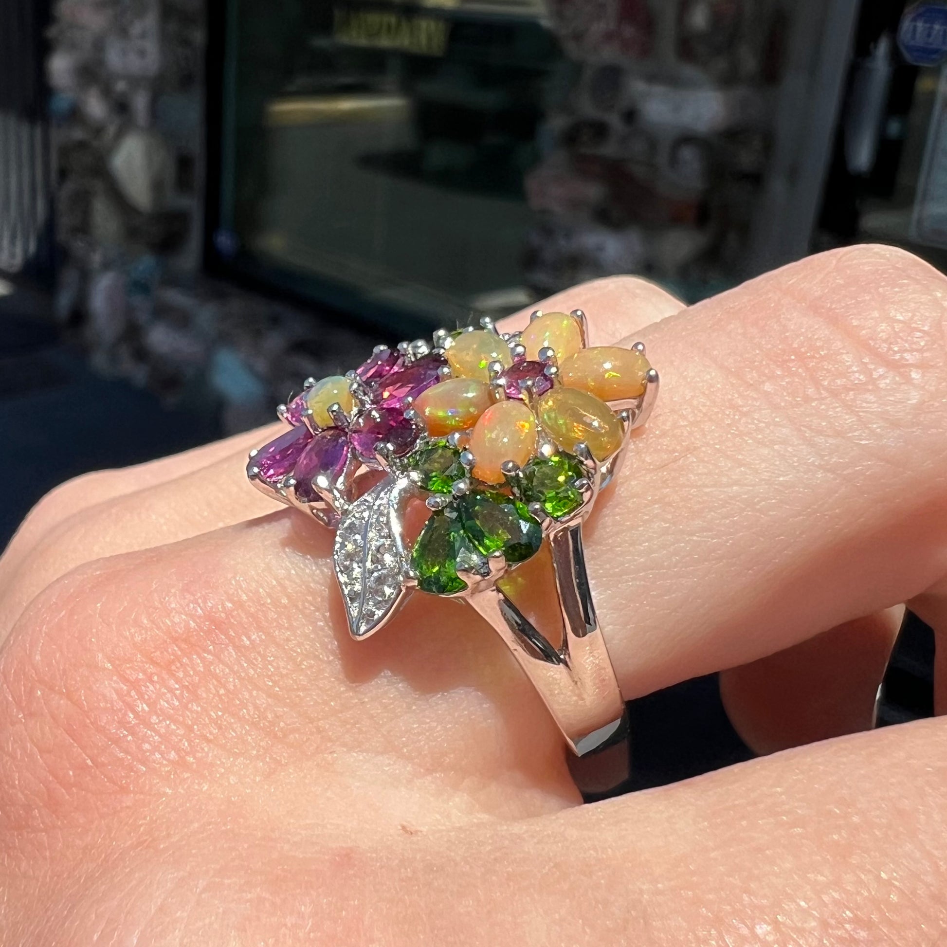 A ladies' gemstone flower design cluster ring set with Ethiopian fire opals, chrome diopsides, rhodolite garnets, and white topaz stones.