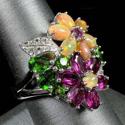 A ladies' gemstone flower design cluster ring set with Ethiopian fire opals, chrome diopsides, rhodolite garnets, and white topaz stones.