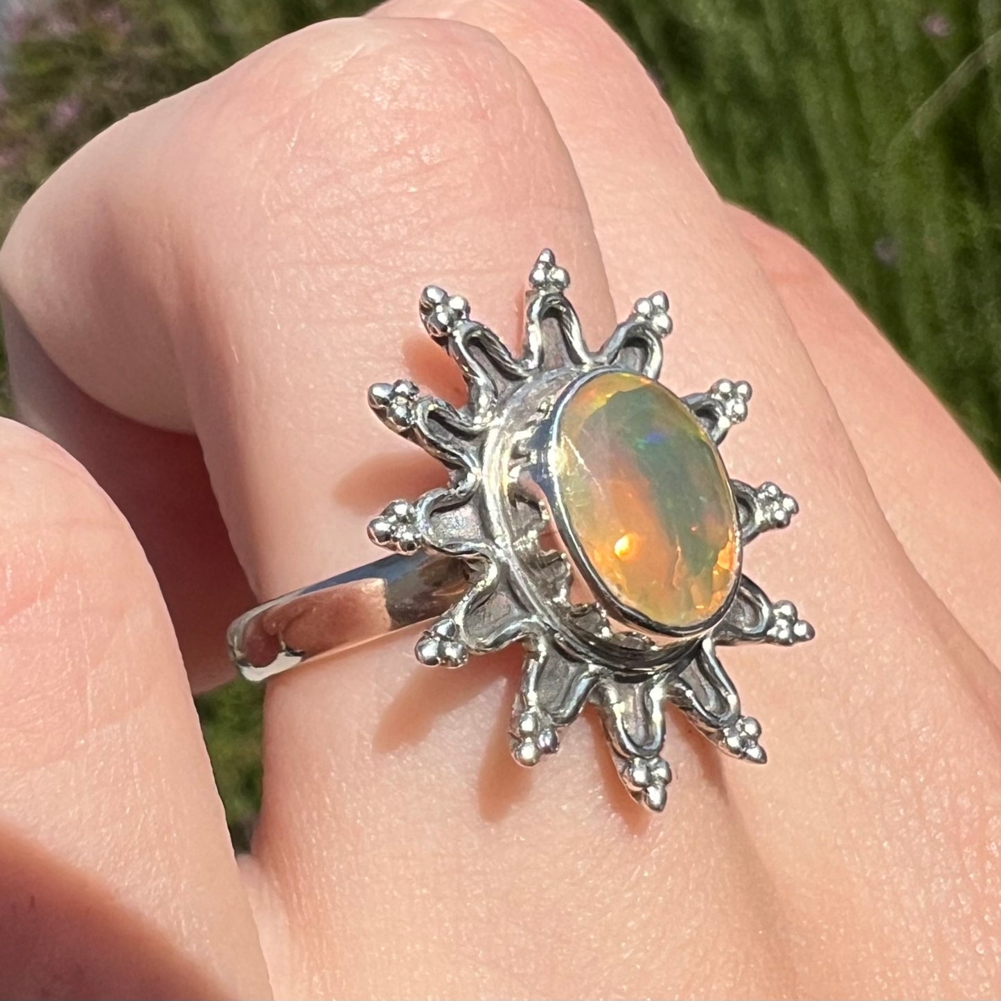 A sterling silver sunburst-style ring mounted with a faceted oval cut Ethiopian fire opal.