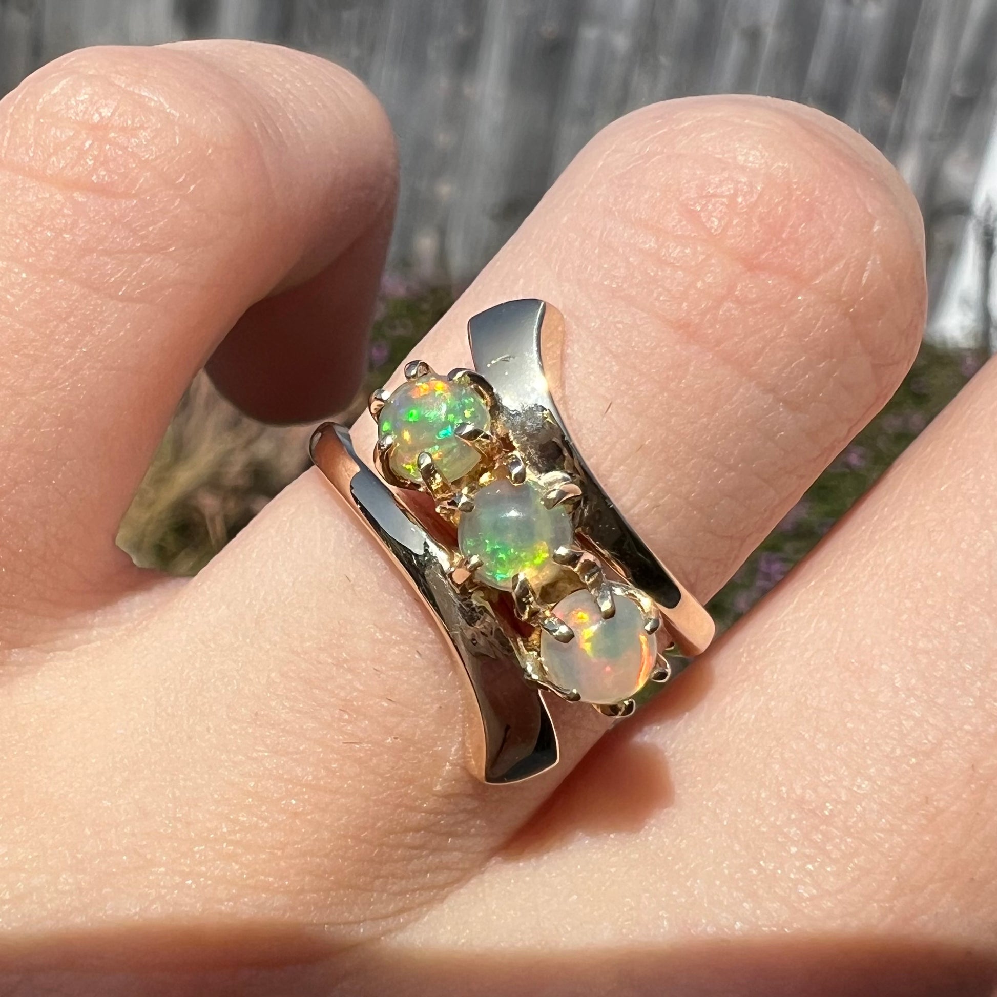 A yellow gold bypass shank ring mounted with three round cabochon cut Ethiopian fire opals.