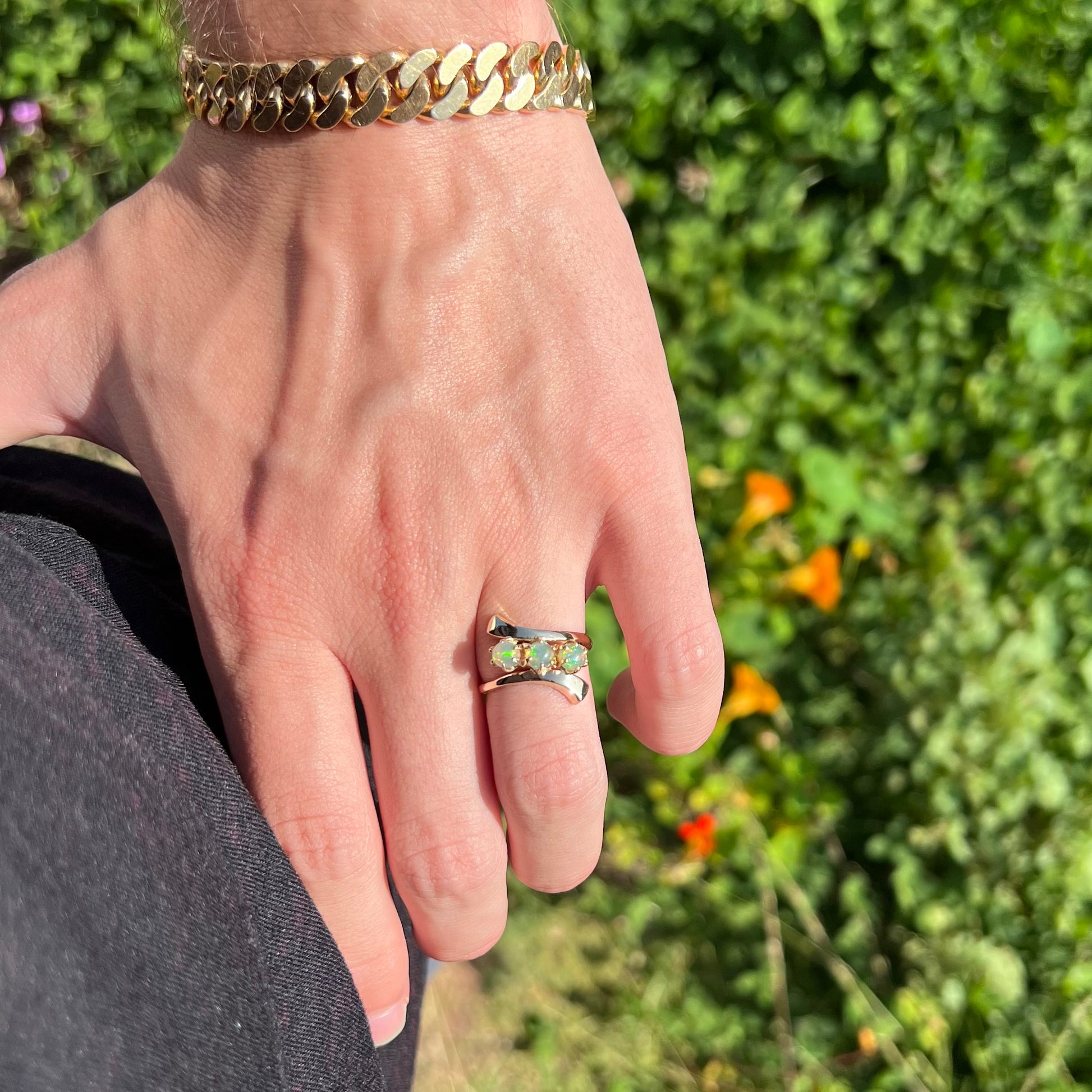 A yellow gold bypass shank ring mounted with three round cabochon cut Ethiopian fire opals.